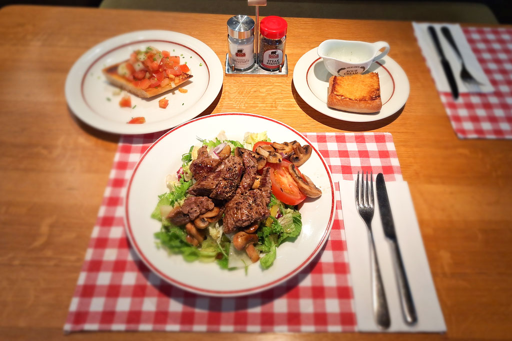 Lunch Time Herzhafte Rindfleischstreifen auf großem Salat mit Beef Bacon, gebratenen  Champignons und BLOCK HOUSE Brot - Block House am Naschmarkt